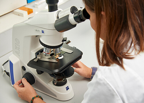 A woman is looking through a microscope