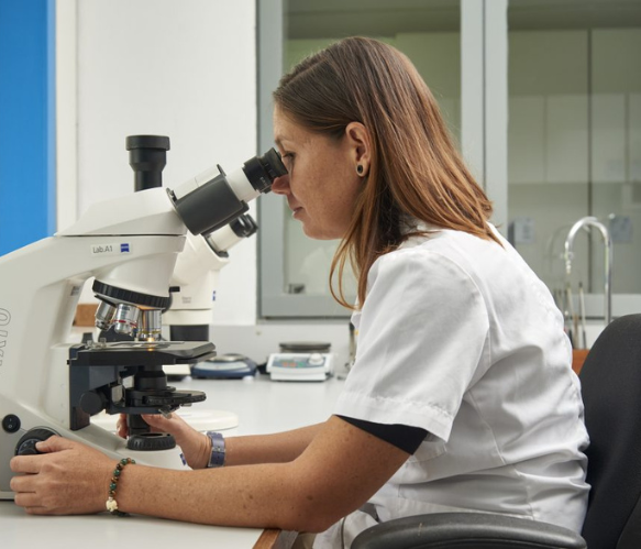 A woman is looking through a microscope